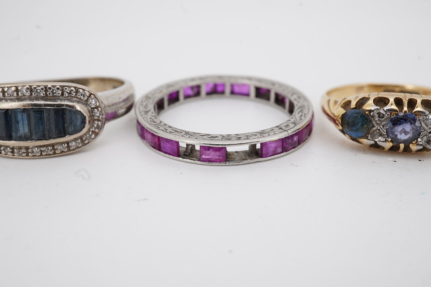A yellow metal and illusion set three stone diamond crossover ring, size I, an 18ct, sapphire and diamond chip set ring, a modern 18ct gold and six stone sapphire set ring, with diamond chip border and an engraved white
